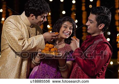 Two men tempting woman to eat sweets View Large Photo Image Stock Photograph - Two men tempting woman to eat sweets. Fotosearch