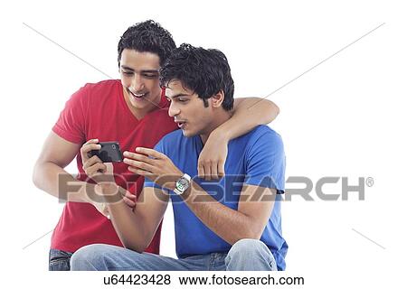 Two young friends sharing photo message over white background View Large Photo Image Stock Photo - Two young friends sharing photo message over white background . Fotosearch