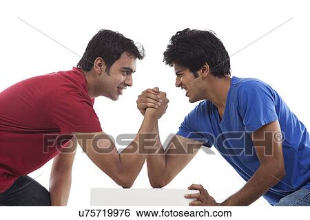 Two young man competing in arm wrestling over white background View Large Photo Image Stock Photograph - Two young man competing in arm wrestling over white background . Fotosearch