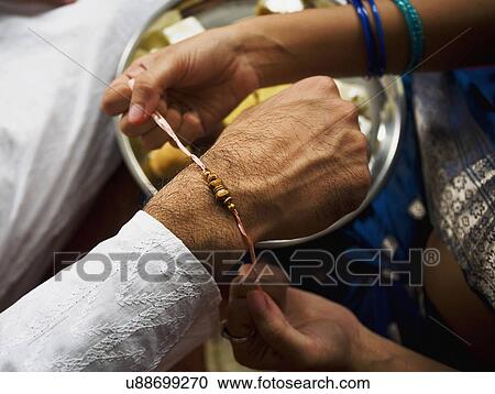 Tying a rakhi on a wrist View Large Photo Image Stock Image - Tying a rakhi on a wrist . Fotosearch