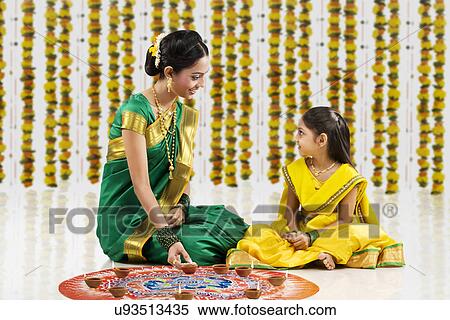 Stock Photography - Woman arranging diyas on a rangoli . Fotosearch