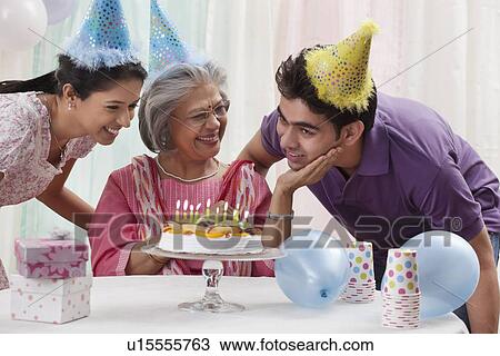 Stock Image - Woman celebrating birthday with grandchildren. Fotosearch