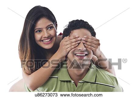 Stock Image - Woman covering mans eyes with her hands. Fotosearch