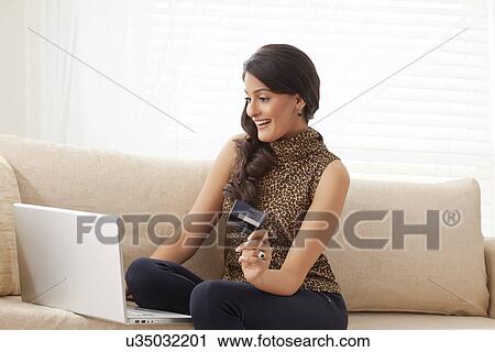 Stock Image - Woman doing net banking on laptop. Fotosearch