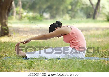 Stock Image - Woman doing stretching exercise at lawn . Fotosearch