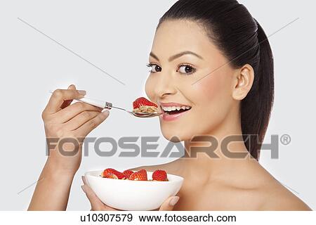 Stock Photo - Woman eating cornflakes with strawberries . Fotosearch