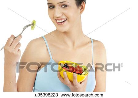 Stock Image - Woman eating fruits from a bowl . Fotosearch