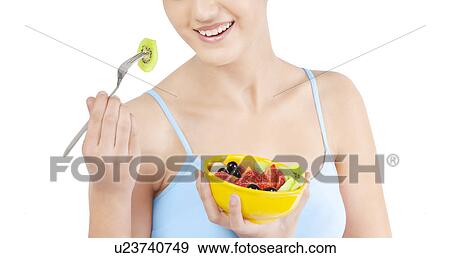 Stock Photo - Woman eating fruits from a bowl . Fotosearch