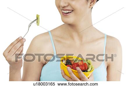 Stock Photography - Woman eating fruits from a bowl . Fotosearch