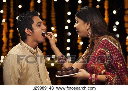 Woman feeding gulab jamun to her brother View Large Photo Image Stock Image - Woman feeding gulab jamun to her brother. Fotosearch