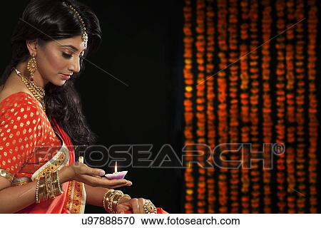 Stock Image - Woman holding a diya. Fotosearch