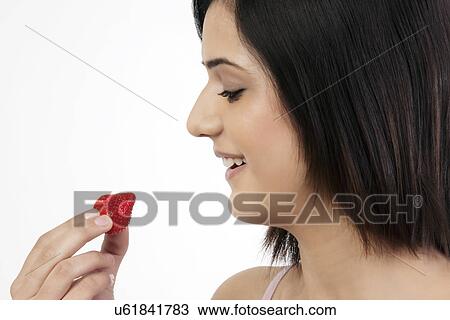Stock Image - Woman holding a strawberry . Fotosearch