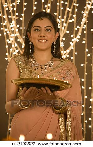 Stock Image - Woman holding a tray of diyas . Fotosearch
