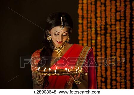 Stock Photo - Woman holding a tray of diyas. Fotosearch