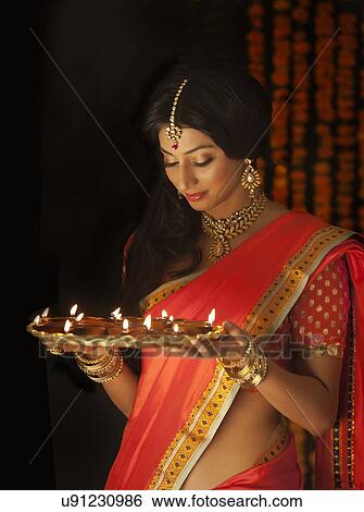 Stock Photograph - Woman holding a tray of diyas. Fotosearch