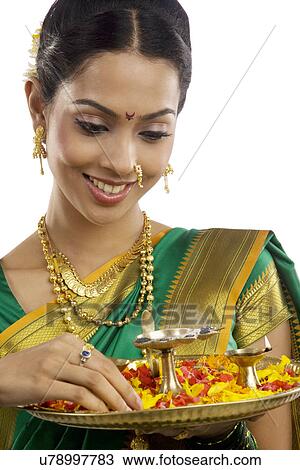 Stock Image - Woman holding a tray with diyas . Fotosearch