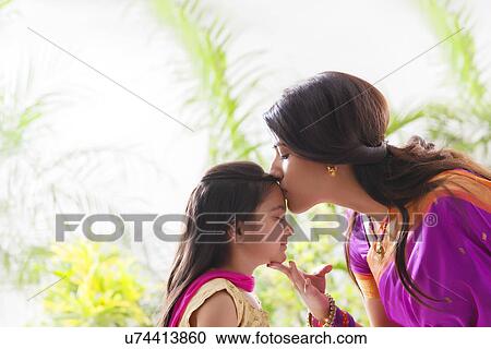 Stock Image - Woman kissing her daughters forehead . Fotosearch