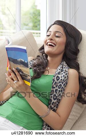 Woman laughing while reading a book View Large Photo Image Stock Image - Woman laughing while reading a book. Fotosearch