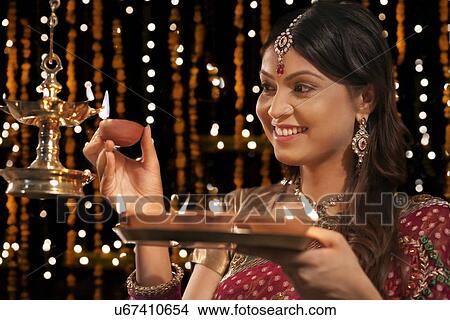 Woman lighting diyas View Large Photo Image Picture - Woman lighting diyas. Fotosearch