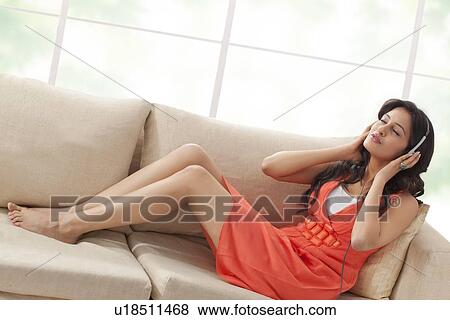 Woman listening to music on a sofa View Large Photo Image Stock Photo - Woman listening to music on a sofa. Fotosearch