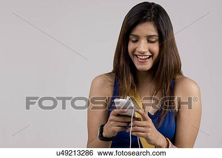 Stock Photograph - Woman listening to music on her phone . Fotosearch