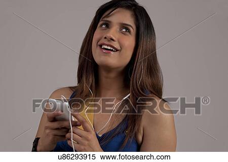Stock Photography - Woman listening to music on her phone . Fotosearch