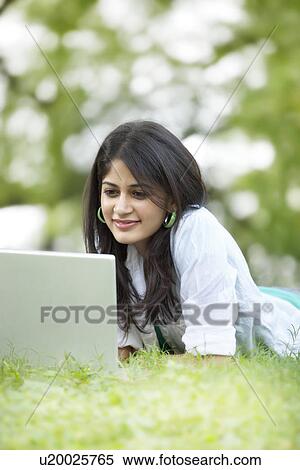 Woman lying on grass and using laptop View Large Photo Image Stock Photography - Woman lying on grass and using laptop . Fotosearch