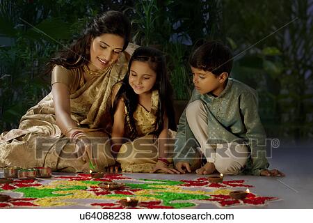 Stock Photo - Woman making a rangoli with her kids . Fotosearch
