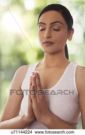 Woman meditating against glass window View Large Photo Image Picture - Woman meditating against glass window. Fotosearch