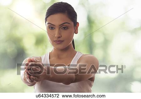 Stock Image - Woman meditating with arms out against glass window. Fotosearch