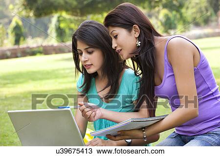 Stock Image - Woman pointing on laptop while taking notes . Fotosearch