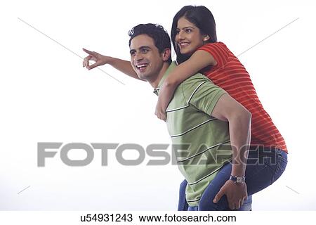 Stock Image - Woman pointing while getting a piggyback ride. Fotosearch