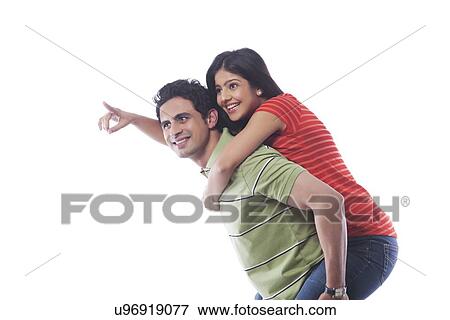 Stock Photo - Woman pointing while getting a piggyback ride. Fotosearch