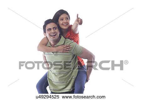 Stock Photography - Woman pointing while getting a piggyback ride. Fotosearch