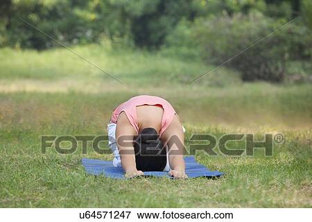 Stock Photo - Woman practicing yoga in lawn . Fotosearch