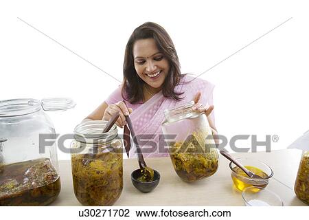 Stock Image - Woman putting pickle into a bowl . Fotosearch