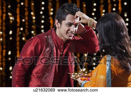 Stock Photo - Woman putting tika on a man. Fotosearch