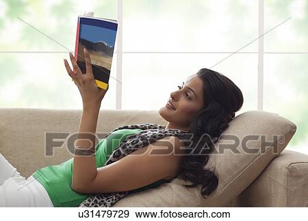 Stock Photo - Woman reading a book on a sofa. Fotosearch