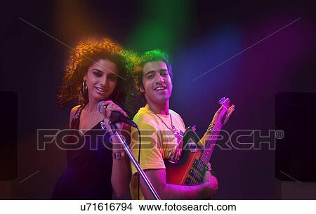 Picture - Woman singing while man plays on the guitar . Fotosearch