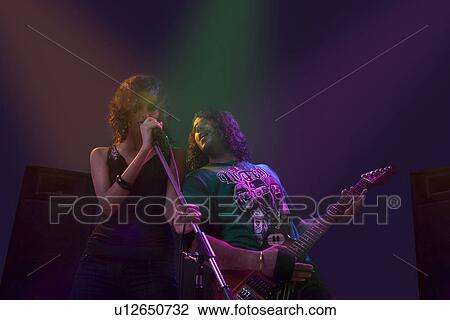 Stock Image - Woman singing while man plays on the guitar . Fotosearch