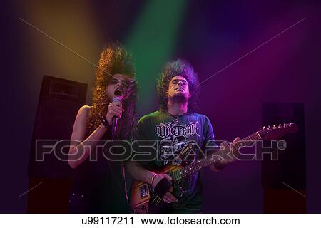 Stock Image - Woman singing while man plays on the guitar . Fotosearch