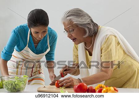 Woman teaching granddaughter how to cut tomato View Large Photo Image Picture - Woman teaching granddaughter how to cut tomato. Fotosearch