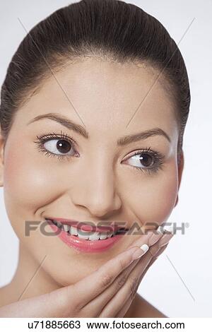 Stock Image - Woman touching her face and looking away . Fotosearch