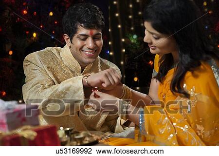Woman tying rakhi on her brother's hand View Large Photo Image Stock Image - Woman tying rakhi on her brother's hand. Fotosearch