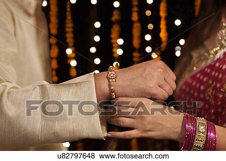 Woman tying rakhi on her brother's hand View Large Photo Image Stock Photo - Woman tying rakhi on her brother's hand. Fotosearch