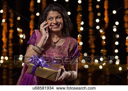 Picture - Woman with a gift talking on a mobile phone. Fotosearch