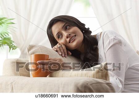 Woman with a mug of tea day dreaming View Large Photo Image Stock Image - Woman with a mug of tea day dreaming. Fotosearch