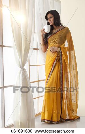 Woman with a mug of tea looking out a window View Large Photo Image Stock Image - Woman with a mug of tea looking out a window. Fotosearch