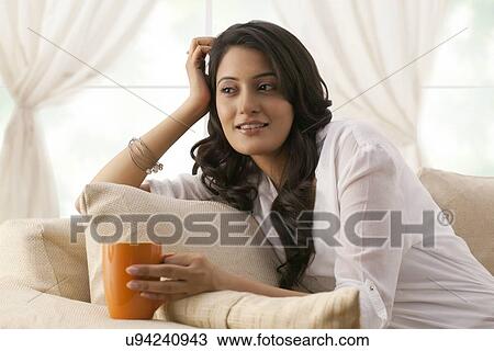 Stock Image - Woman with a mug of tea thinking. Fotosearch