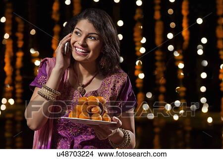 Woman with a plate of sweets talking on mobile phone View Large Photo Image Picture - Woman with a plate of sweets talking on mobile phone. Fotosearch